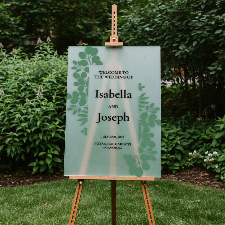 Outdoor wedding welcome sign for Isabella and Joseph with green leaf design on easel in botanical garden