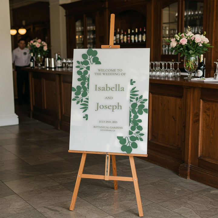 Wedding welcome sign for Isabella and Joseph with green leaf design on wooden easel at indoor venue