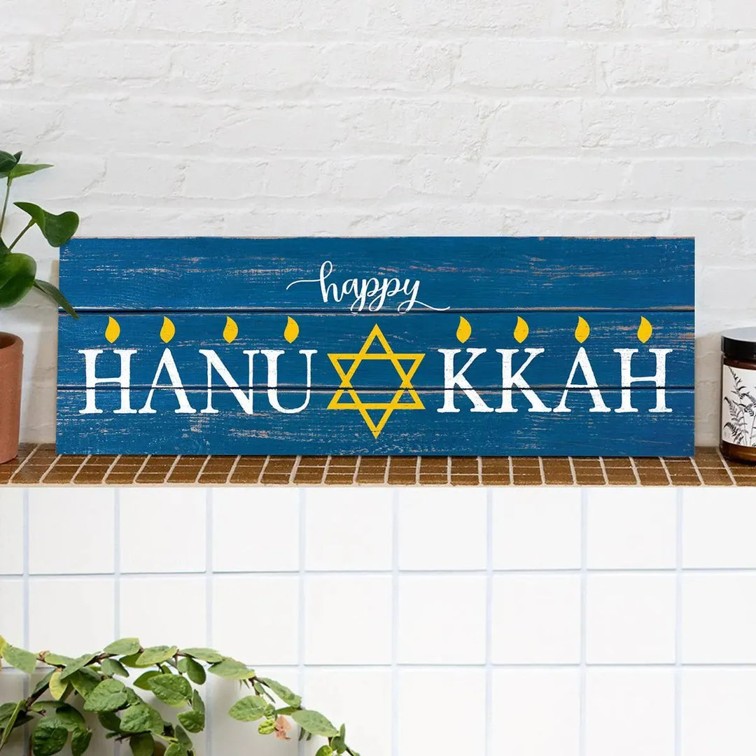 Blue wood Happy Hanukkah sign with Star of David and yellow candle flames on a mantel