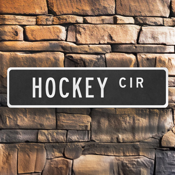 black metal street sign reading Hockey Cir on a rustic brown stone wall background