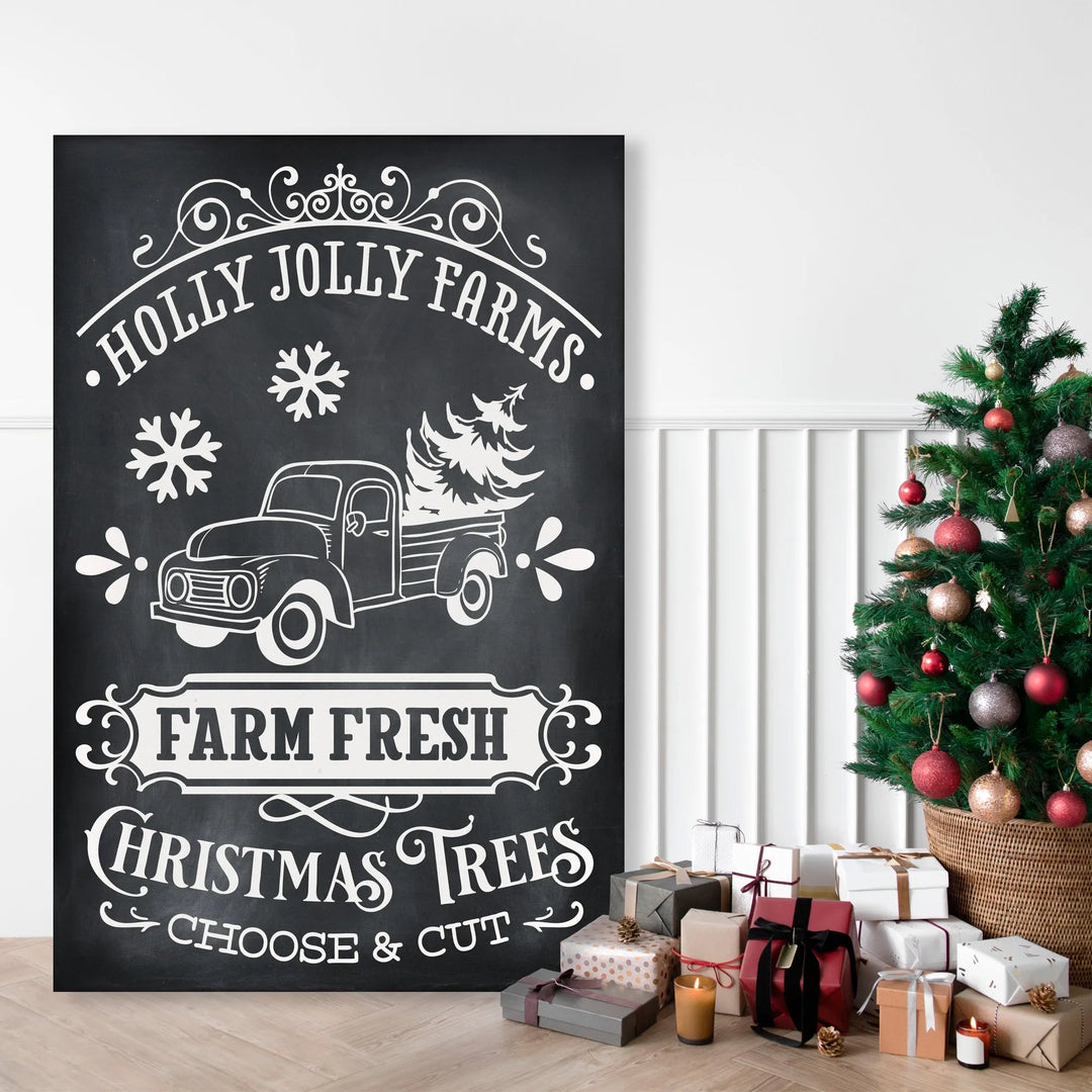 Black chalkboard sign with vintage truck and Christmas tree illustration, text Holly Jolly Farms Farm Fresh Christmas Trees, next to decorated Christmas tree and presents