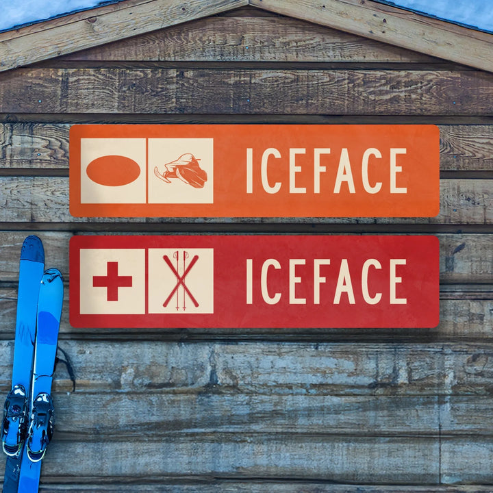 Orange and red Iceface ski trail metal signs on wooden wall with blue skis leaning beside them