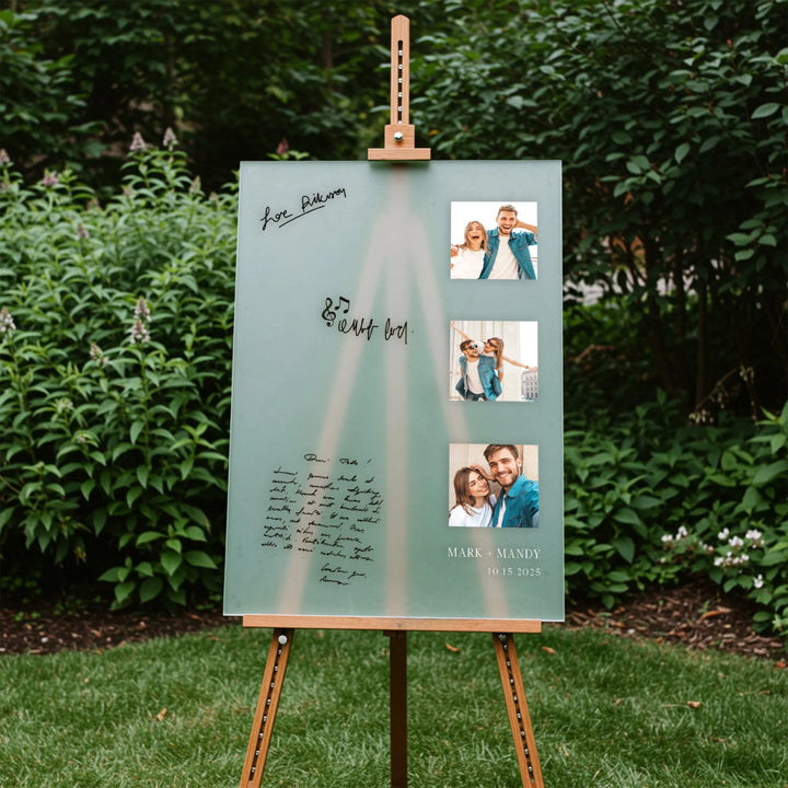 Frosted glass wedding guest book sign with couple photos and handwritten notes on wooden easel