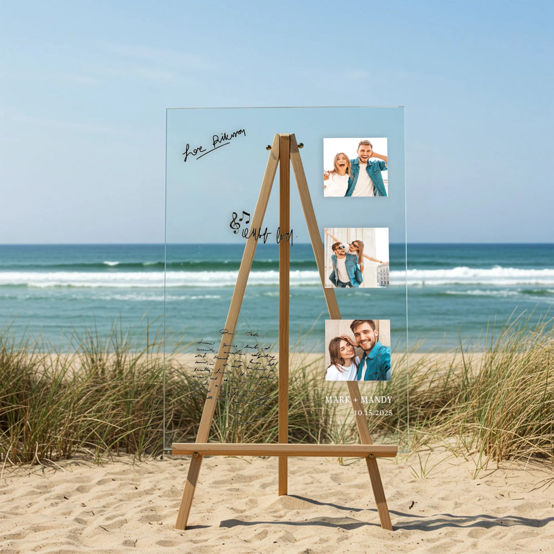 Transparent acrylic wedding guest book with couple photos on wooden easel at sandy beach