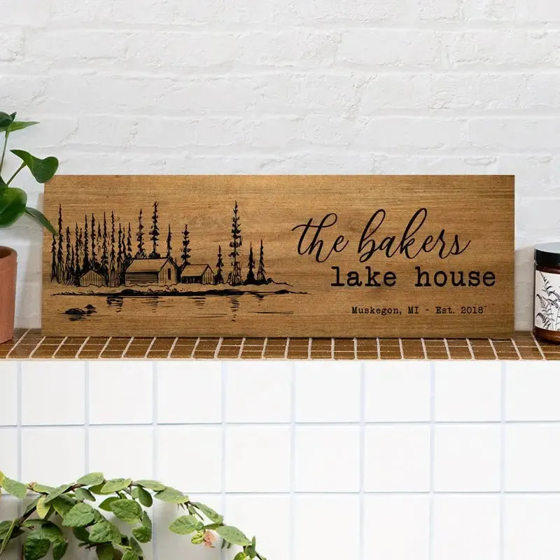 Custom wood lake house sign with cabin, trees, and Muskegon MI engraving on a shelf