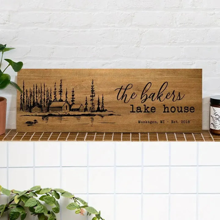 Custom wood lake house sign with cabin, trees, and Muskegon MI engraving on a shelf