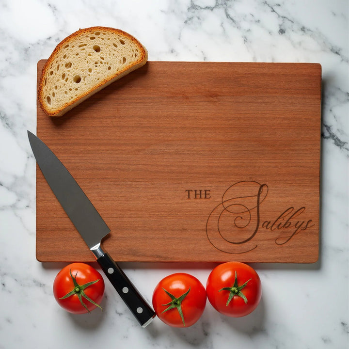 Personalized wooden cutting board engraved with 'The Salibys', knife, bread, and tomatoes