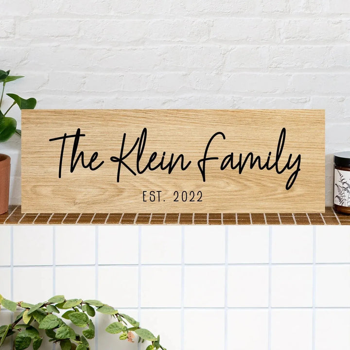 Custom wood family name sign with 'The Klein Family Est. 2022' on a shelf, home decor