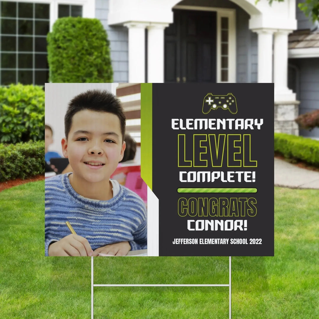 Elementary school graduation yard sign with a smiling boy and text level complete congrats Connor