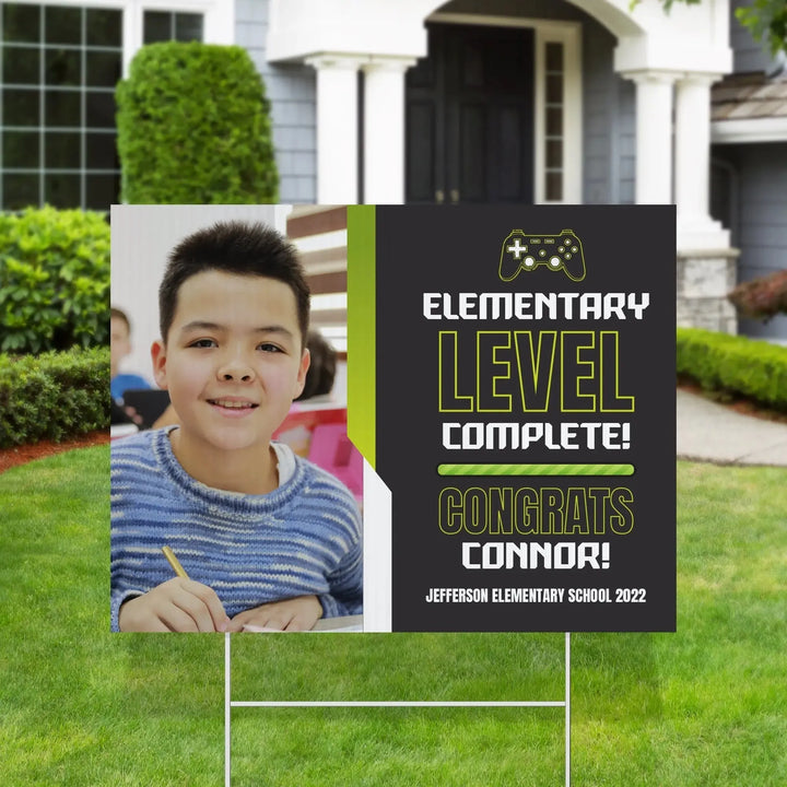 Elementary school graduation yard sign with a smiling boy and text level complete congrats Connor