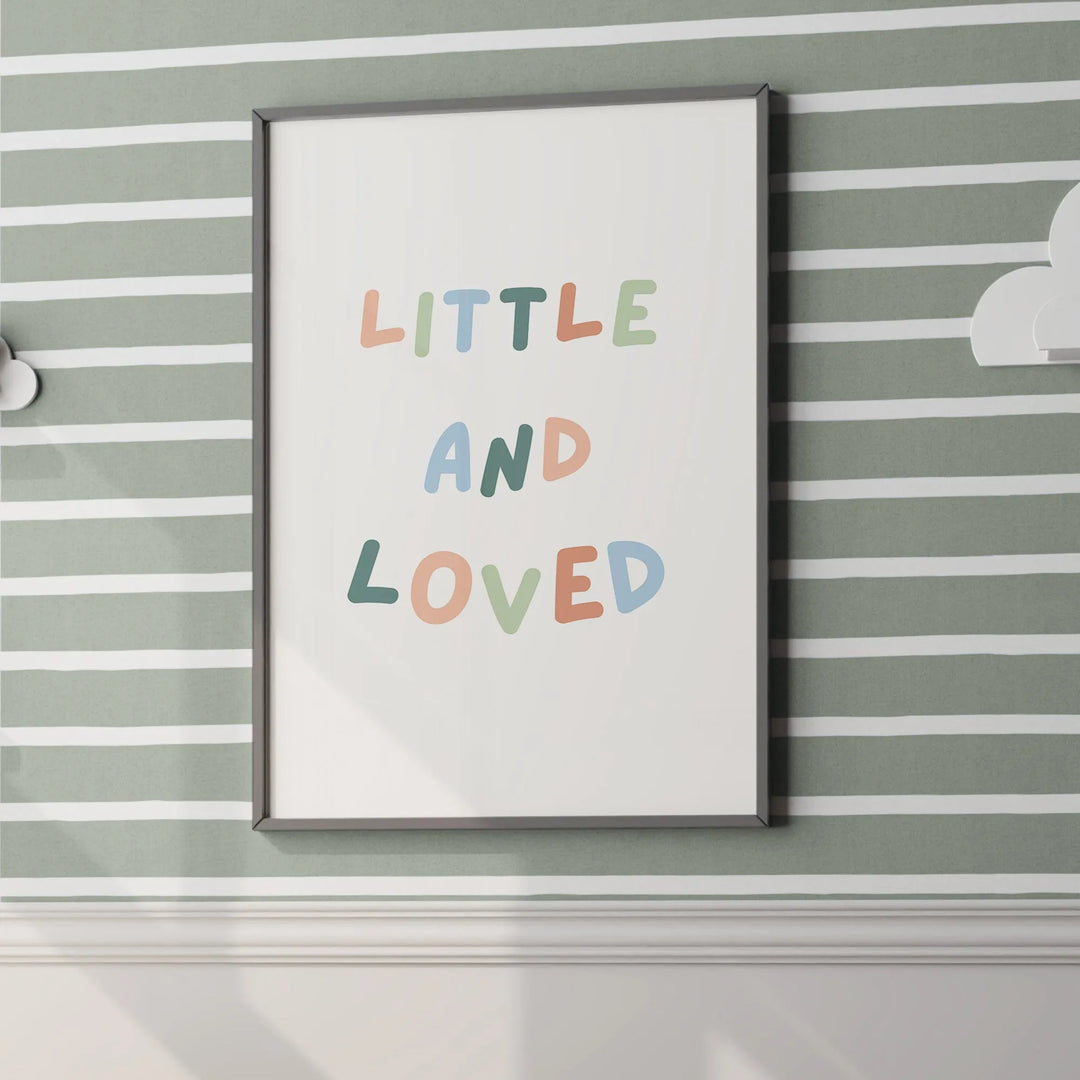 Framed nursery wall art with colorful letters spelling Little and Loved on green striped wall