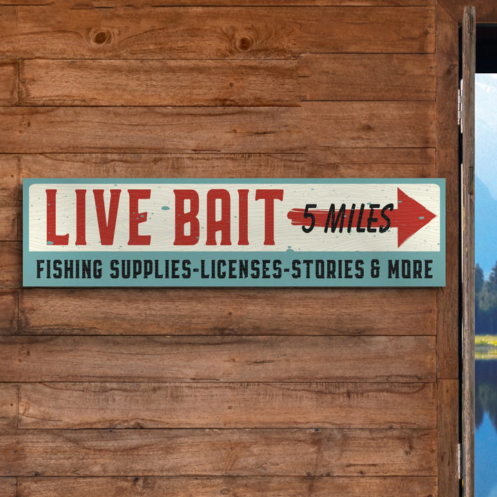 Wooden wall with vintage live bait sign pointing 5 miles to fishing supplies and licenses