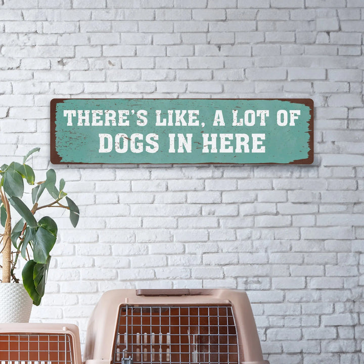 Rustic metal sign on white brick wall reading there's like, a lot of dogs in here, above dog crates and green potted plant
