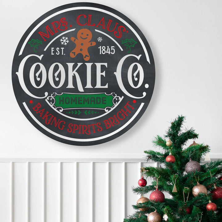 Round Mrs. Claus Cookie Co. metal sign with gingerbread man and Christmas decor above wainscoting