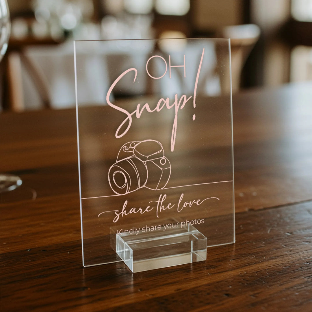 Clear acrylic wedding table sign with pink text Oh Snap! share the love and camera illustration