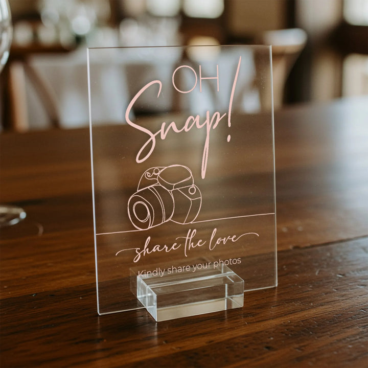 Clear acrylic wedding table sign with pink text Oh Snap! share the love and camera illustration