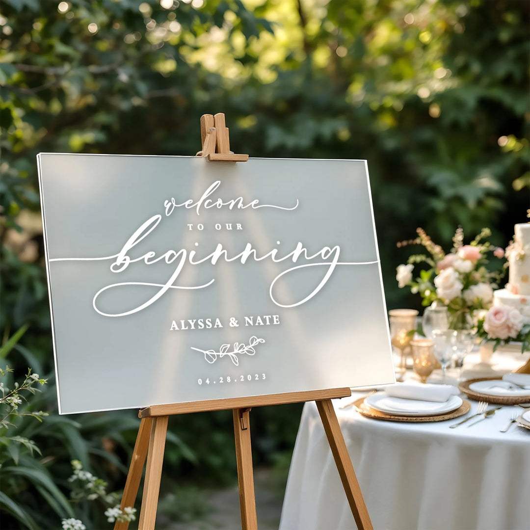 Wedding welcome sign on wooden easel with Alyssa and Nate names and floral wedding table setup