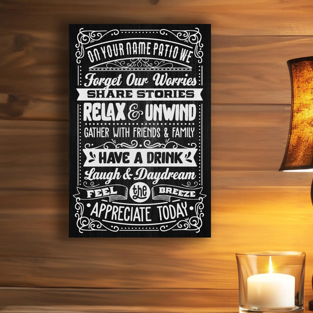 Black metal patio rules sign with white lettering on wooden wall, candle and lamp nearby