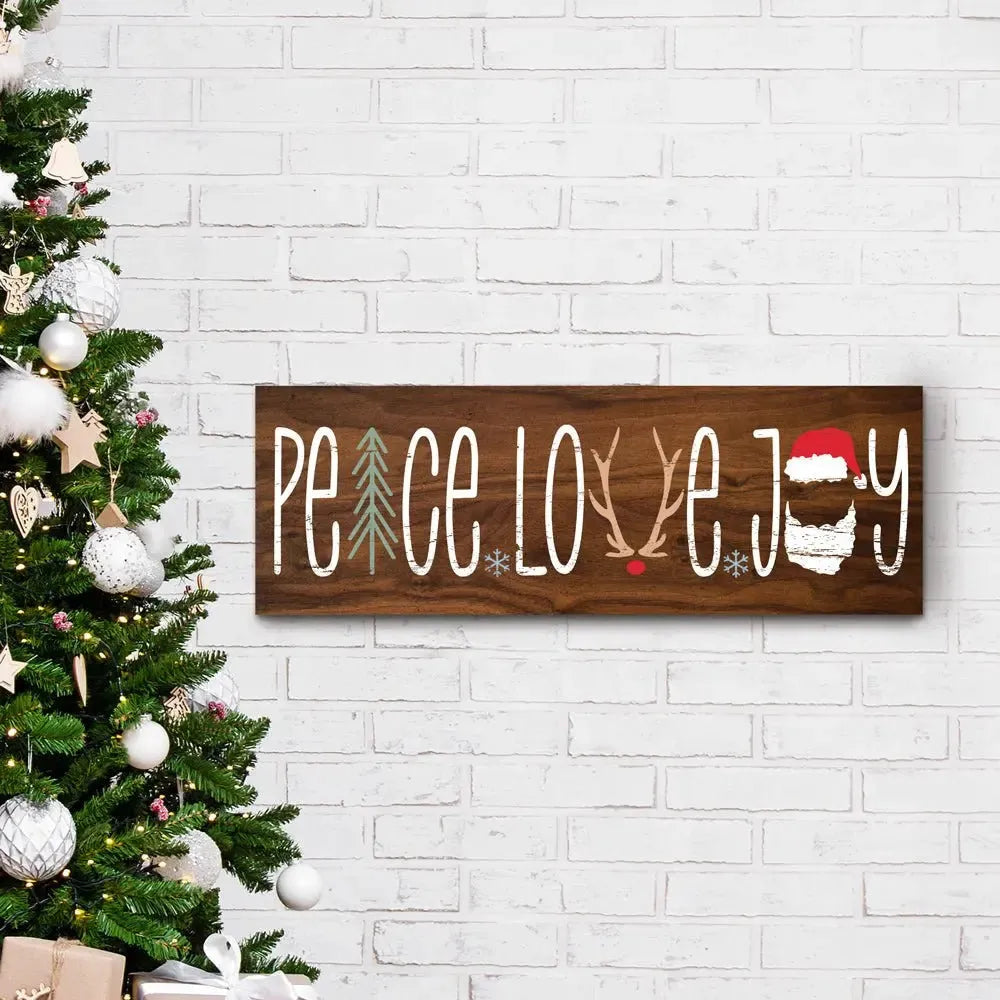 Peace Love Joy wood Christmas sign on white brick wall next to decorated tree
