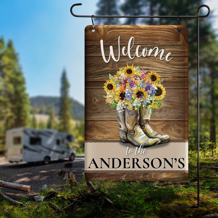 Personalized garden flag with cowboy boots filled with flowers and Welcome to the Anderson's text outdoors