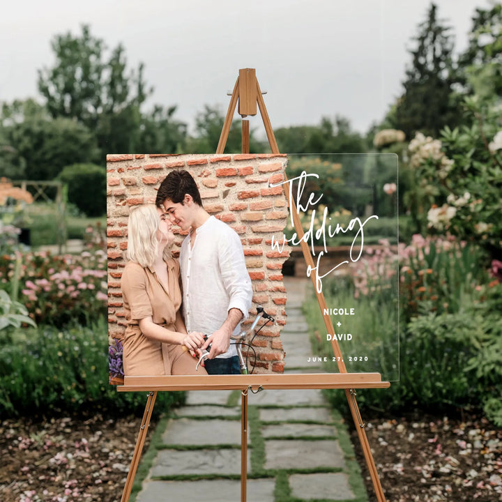 Wedding welcome sign on easel with couple photo and text Nicole + David June 27, 2020 in garden