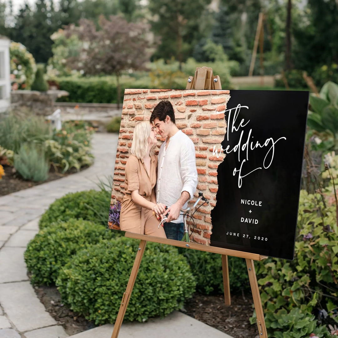 Outdoor wedding welcome sign on wooden easel featuring couple photo and wedding details
