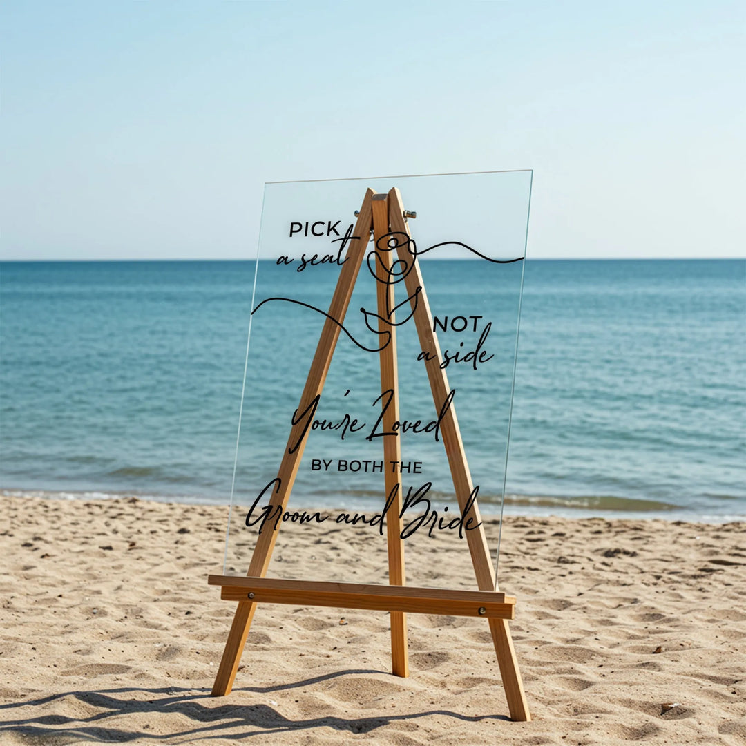 Acrylic wedding welcome sign on wooden easel on sandy beach with ocean background