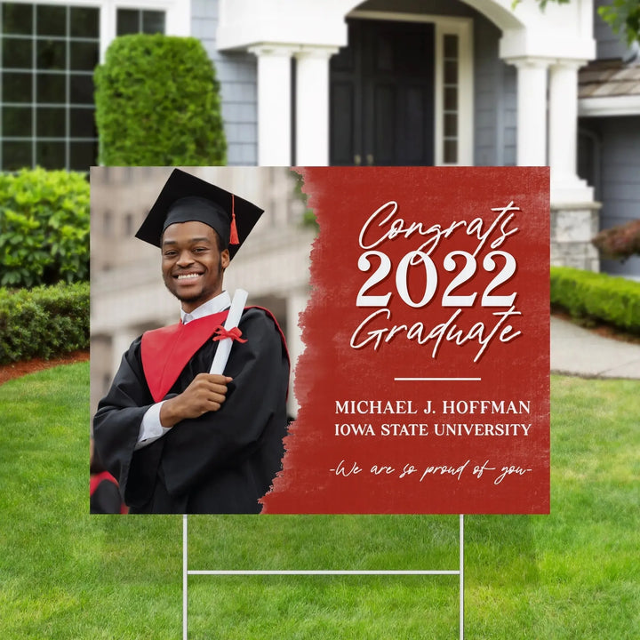 Yard sign with photo of smiling male graduate in cap and gown, red background with Congrats 2022 Graduate text