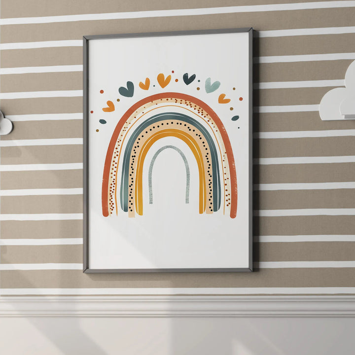 Framed colorful rainbow wall art with hearts above, hanging on beige and white striped nursery wall