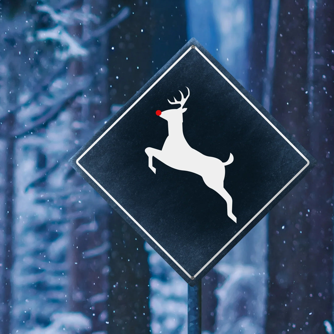 Black diamond sign with white leaping reindeer and red nose in snowy forest