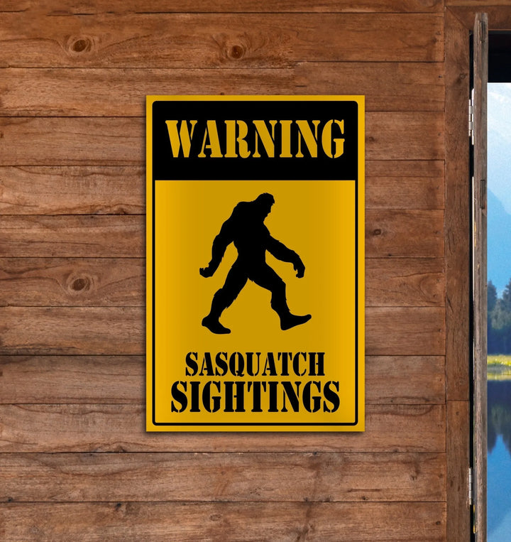 Yellow and black warning sign with Bigfoot silhouette and text Sasquatch sightings on wooden wall