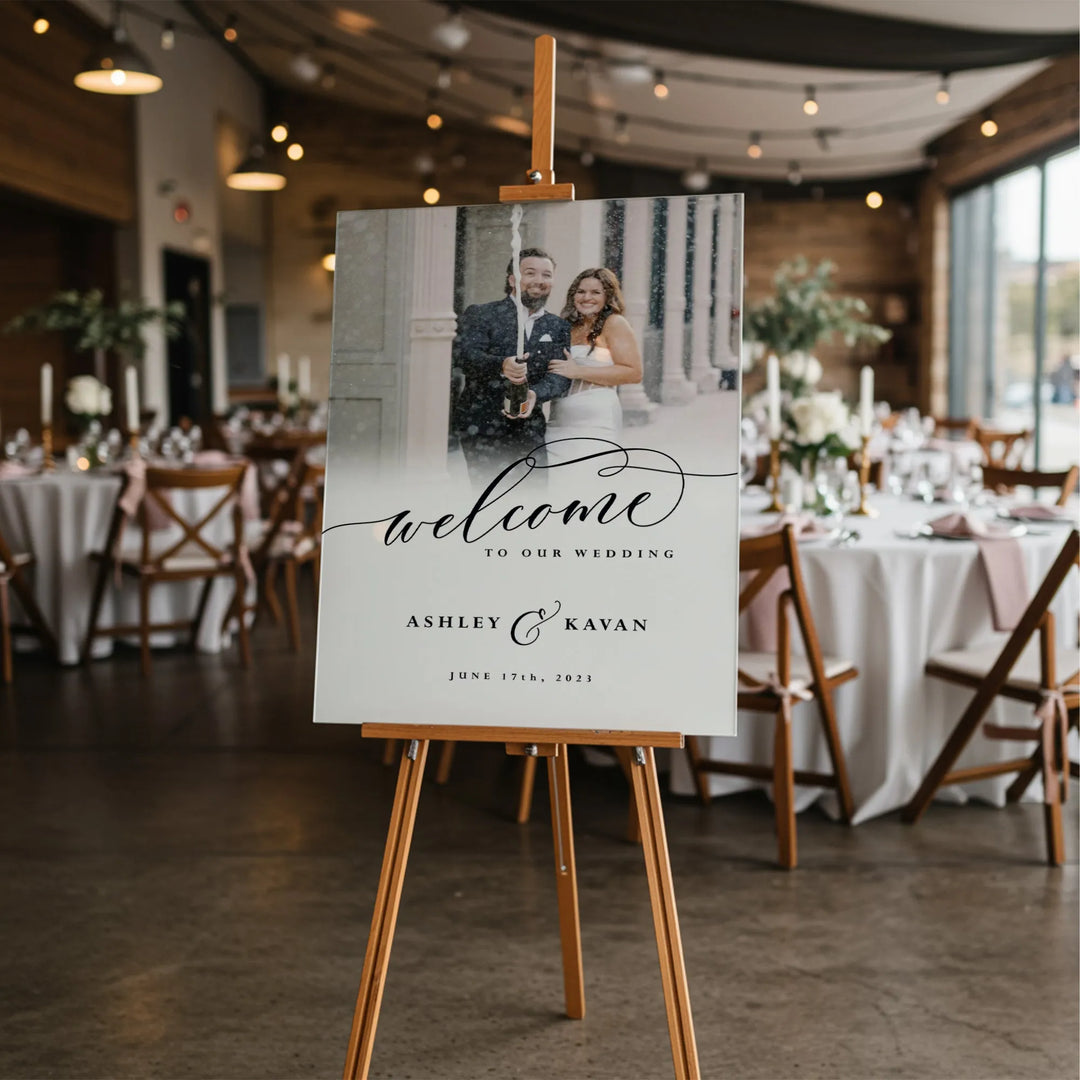 Wedding welcome sign with bride and groom photo, elegant script, wooden easel in reception hall