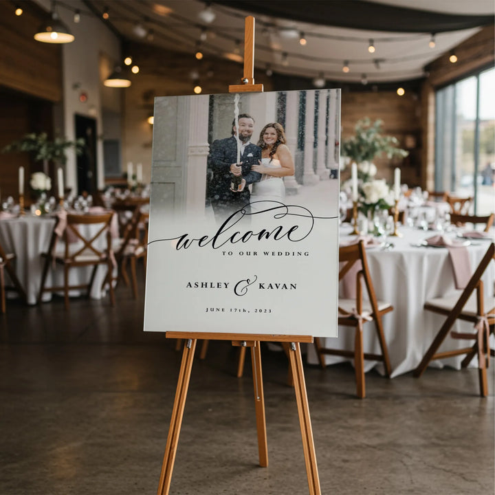 Wedding welcome sign with bride and groom photo, elegant script, wooden easel in reception hall