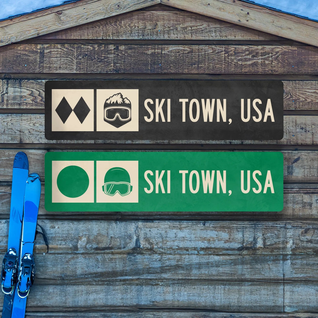 Two Ski Town, USA metal trail signs on wooden wall with blue skis leaning beside them