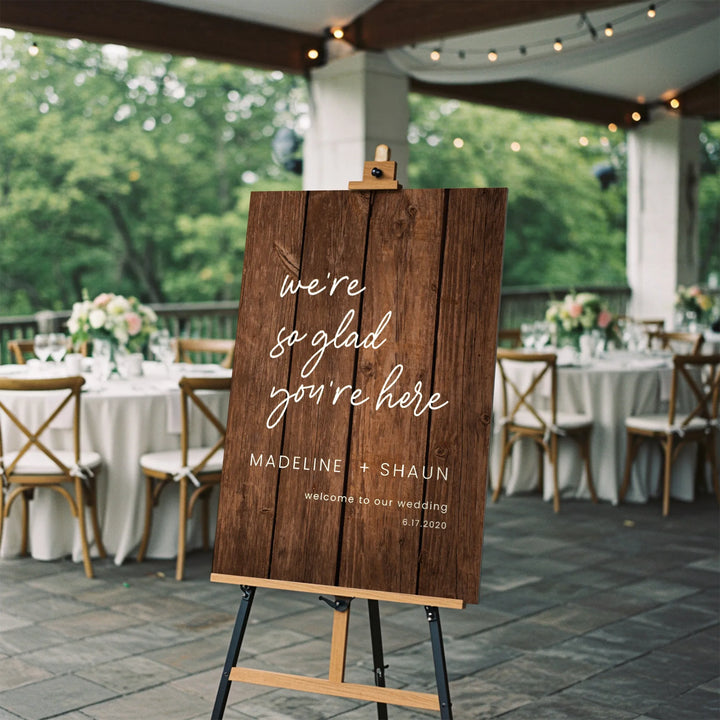 Rustic wooden wedding welcome sign on easel with floral decorated reception tables