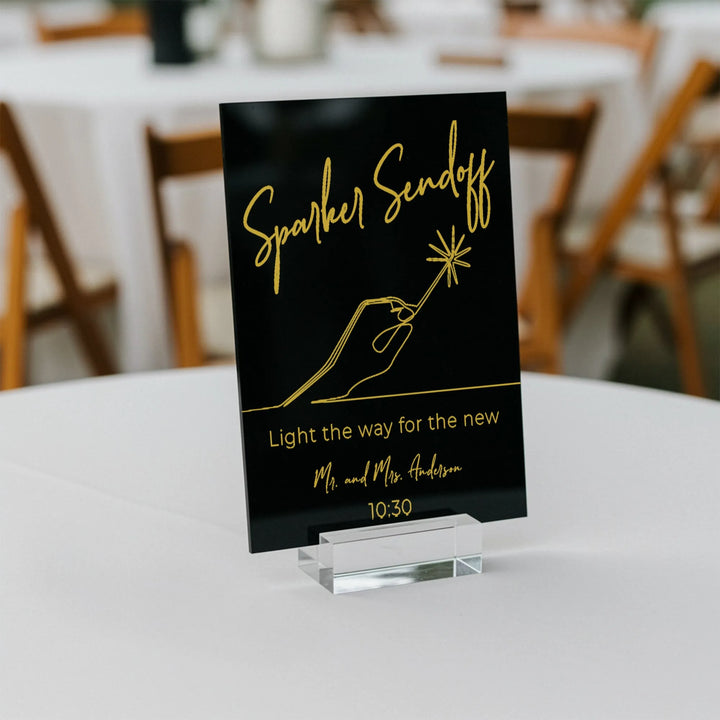 Black wedding table sign with gold text Sparkler Sendoff and hand holding sparkler graphic