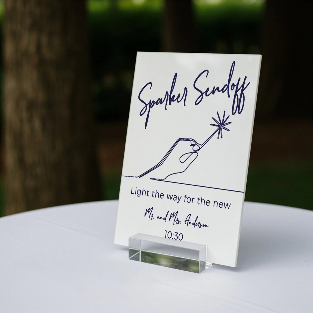 White wedding sparkler sendoff sign on white table with hand illustration and event time
