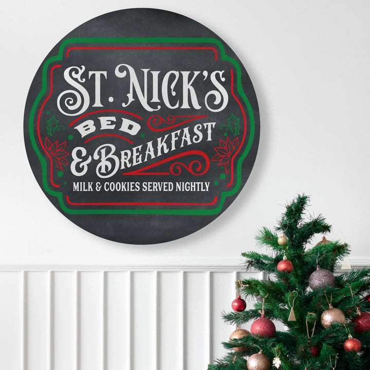 Round St. Nick's Bed & Breakfast metal sign with holiday-themed red and green accents, near decorated Christmas tree