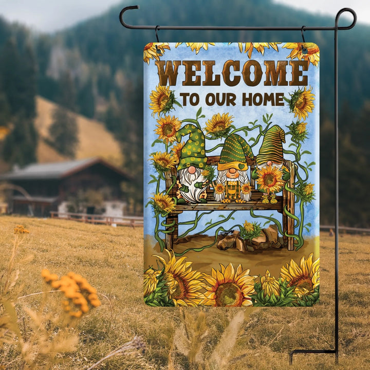 Garden flag with gnomes, sunflowers, and text 'Welcome to Our Home' in rustic outdoor setting