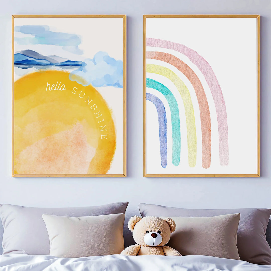 Watercolor nursery wall art with framed sunshine and rainbow designs above bed with teddy bear