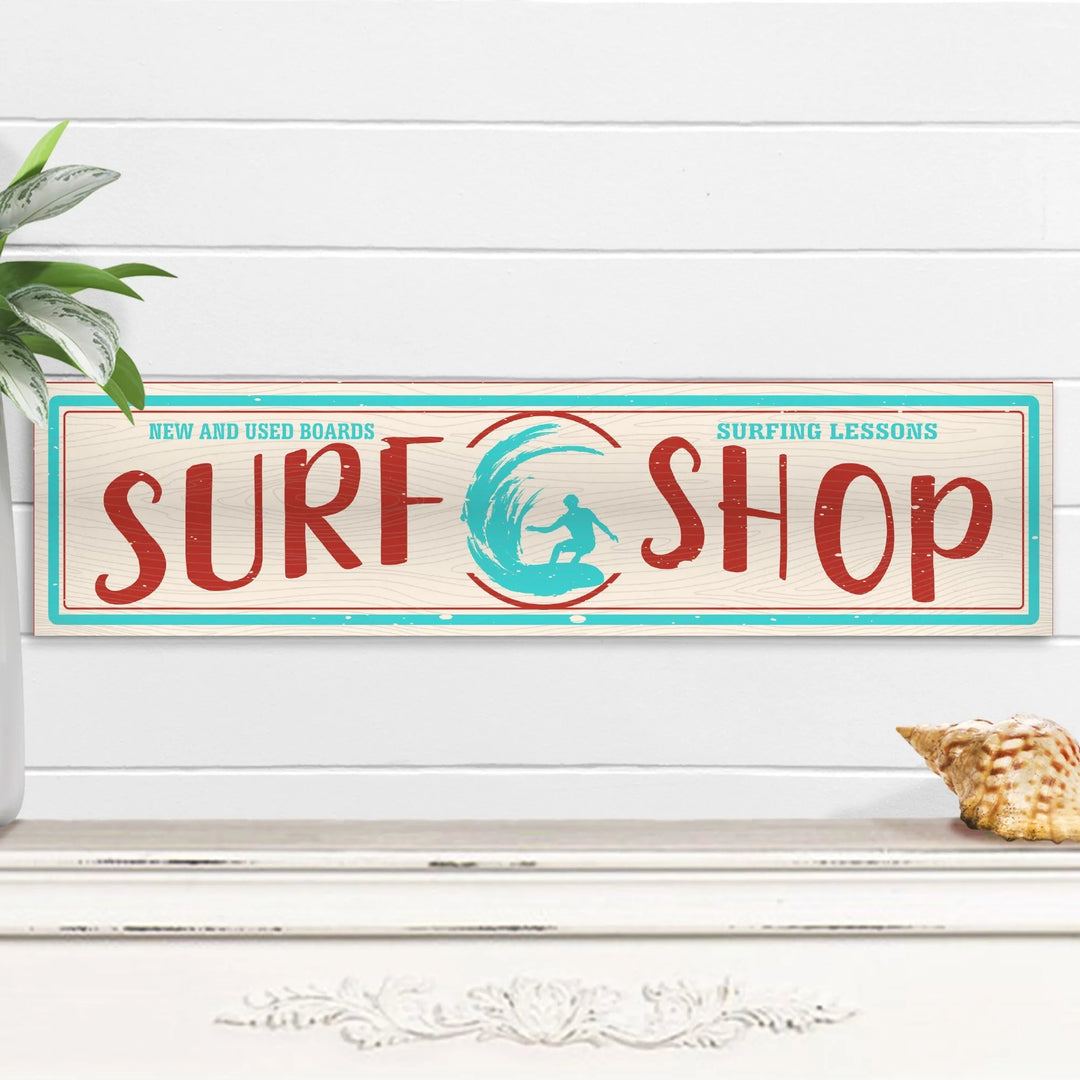 Rectangular surf shop sign with surfer graphic, advertising new and used boards and lessons