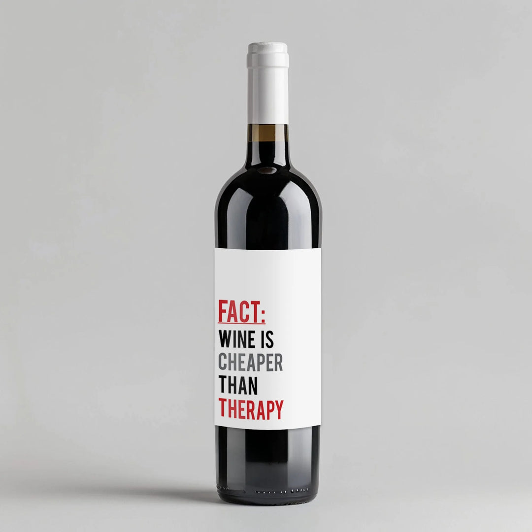 Wine bottle with white label reading 'FACT: WINE IS CHEAPER THAN THERAPY' on gray background