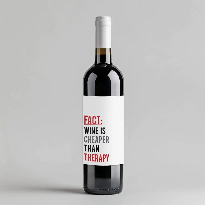 Wine bottle with white label reading 'FACT: WINE IS CHEAPER THAN THERAPY' on gray background