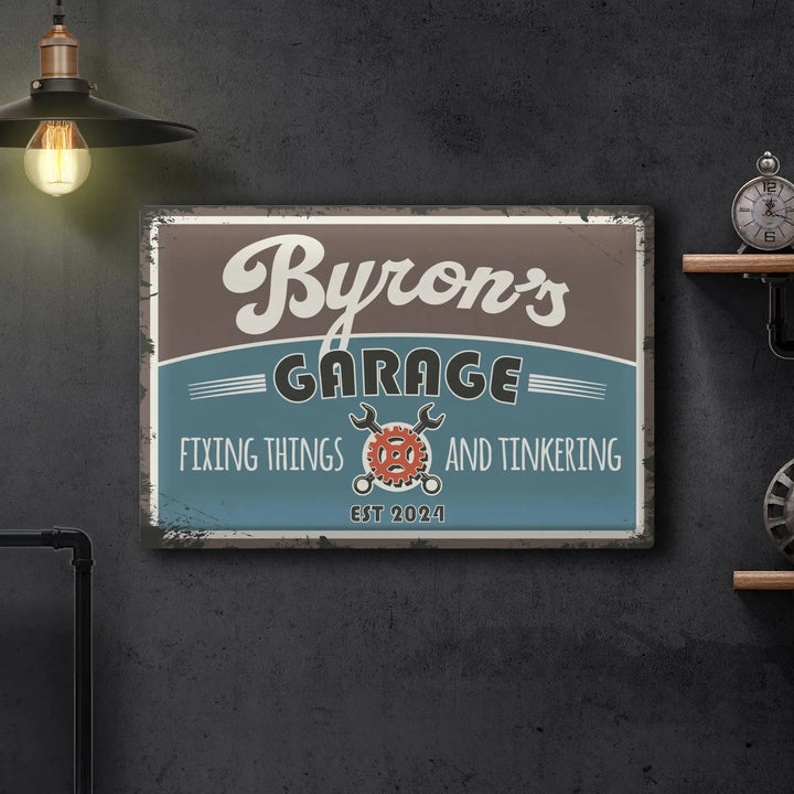 Vintage metal sign reading Byron's Garage fixing things and tinkering established 2024 on gray wall