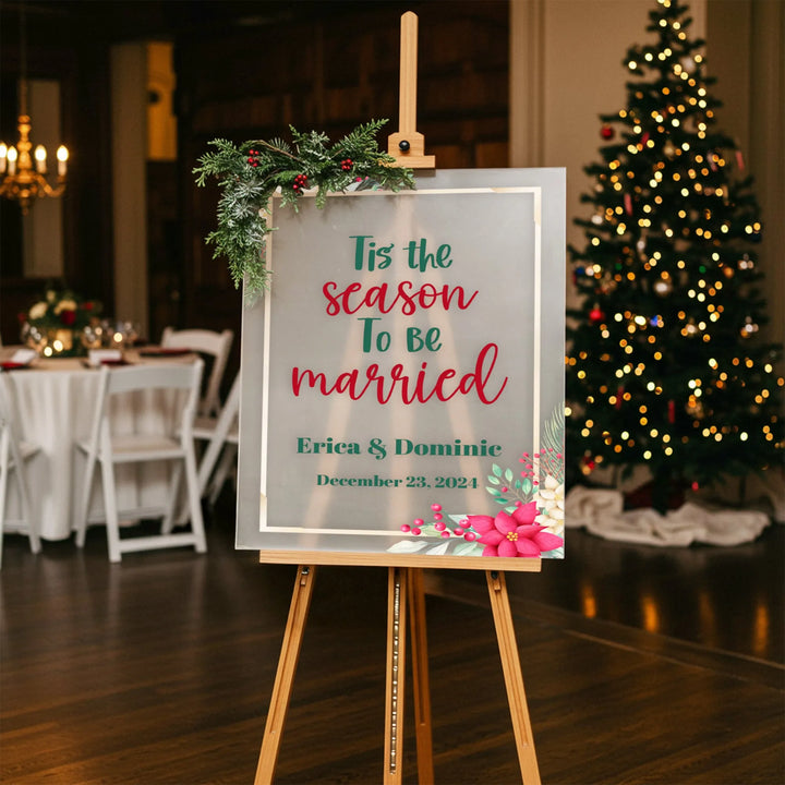 Holiday wedding welcome sign with festive greenery, poinsettias, and Christmas tree in background