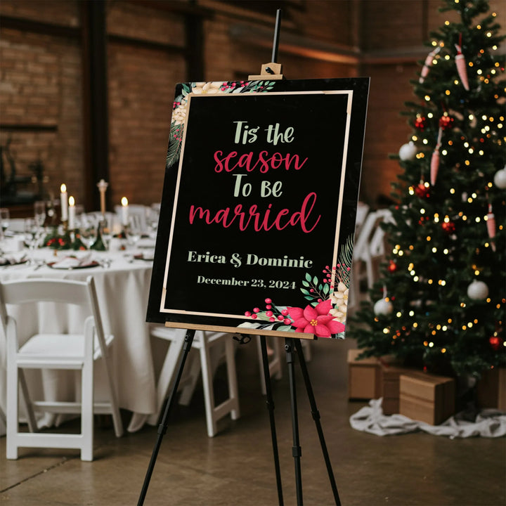 Holiday wedding welcome sign with floral design and Christmas tree in festive reception hall