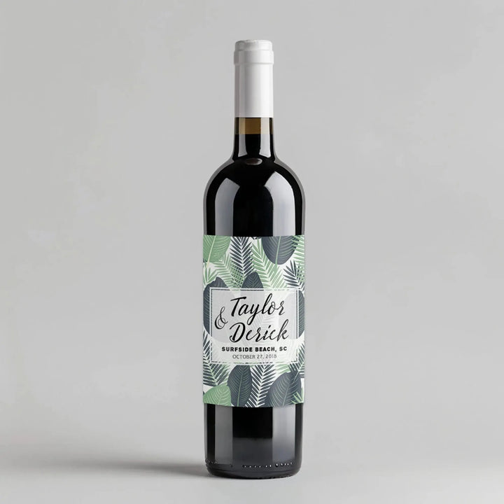 Wine bottle with tropical leaves label and personalized text on a gray background