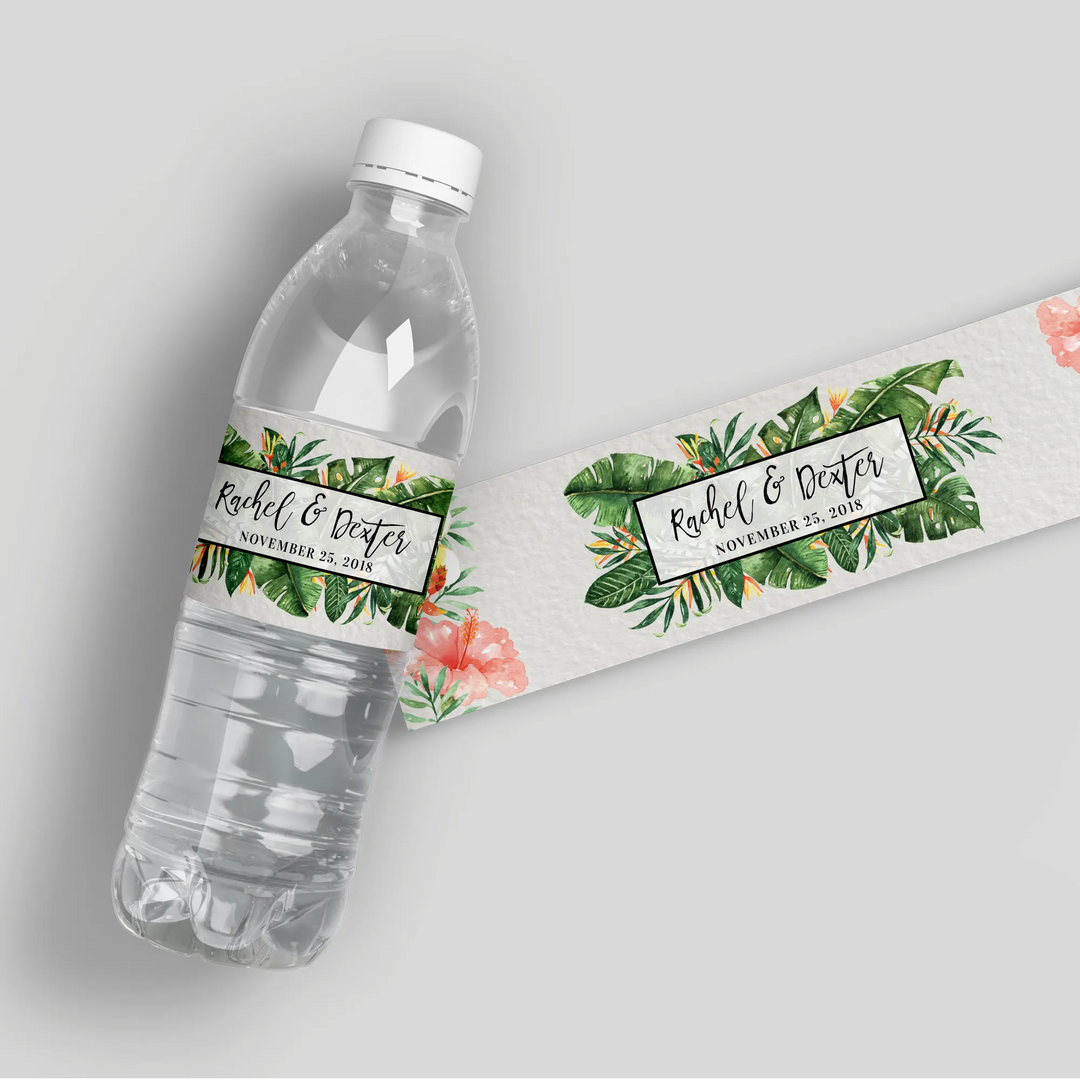 Tropical wedding water bottle label with green leaves, flowers, and custom names.