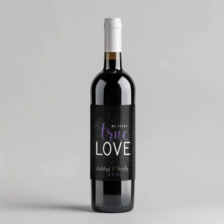 Red wine bottle with custom black 'true love' wedding label on a plain background