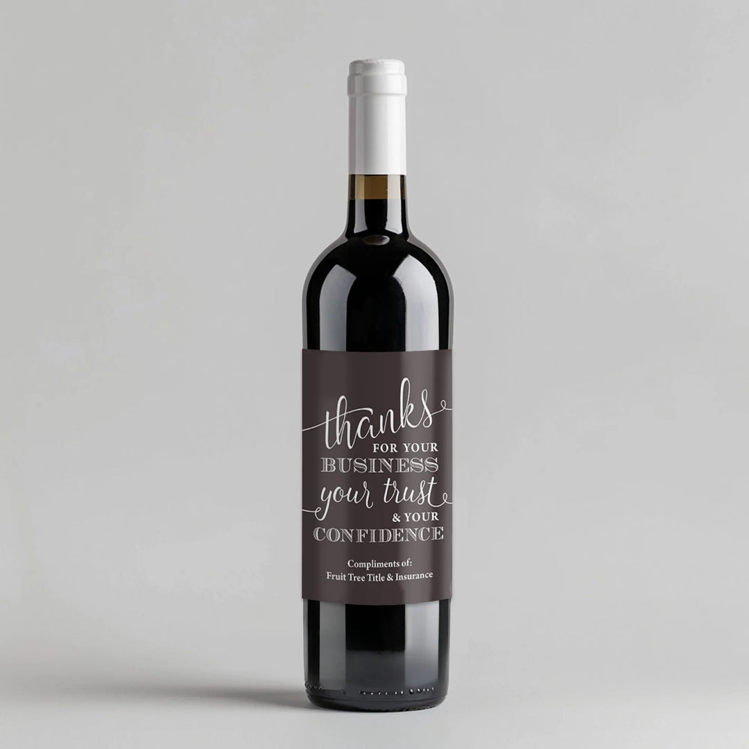 Wine bottle with custom business thank you label on plain gray background